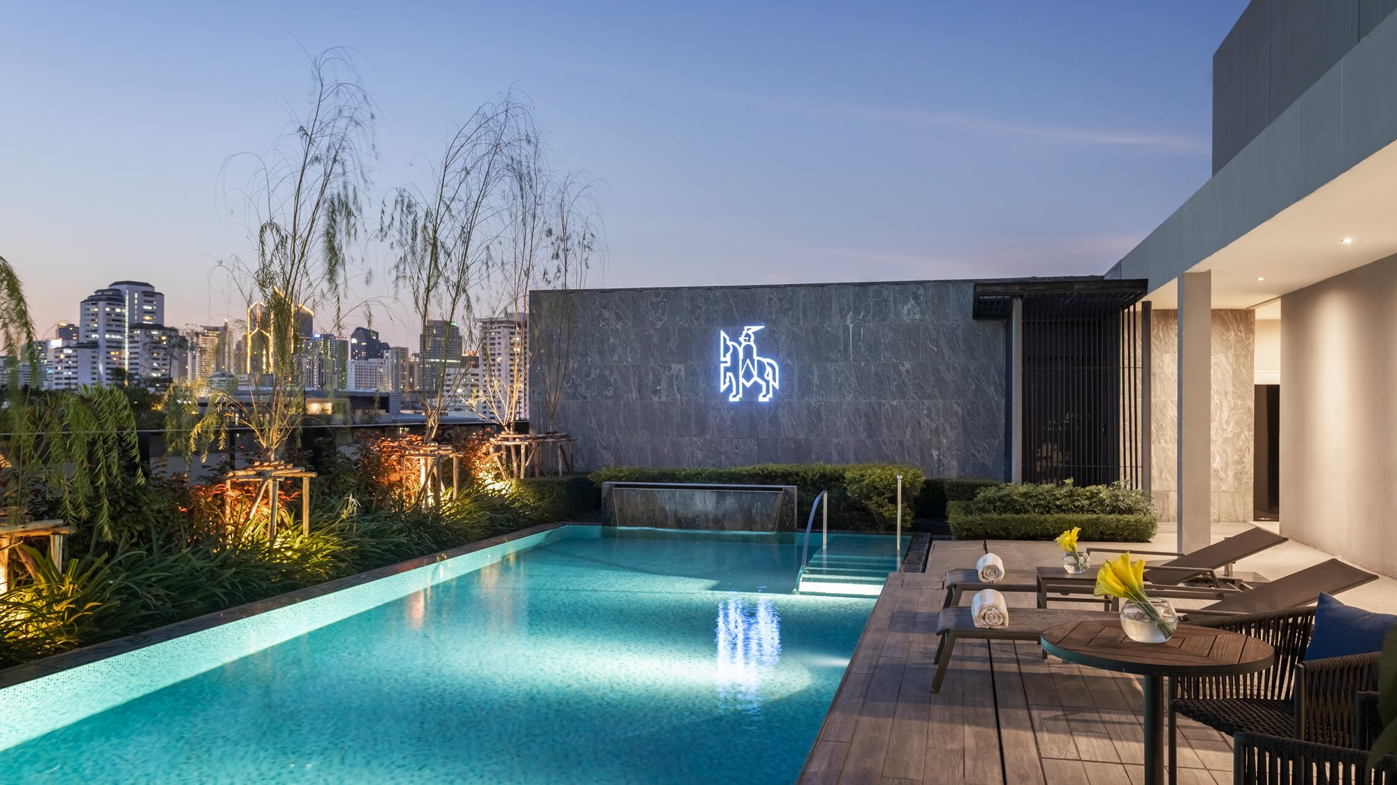 Illuminated Walton Suites rooftop pool and horse-and-rider emblem in the evening