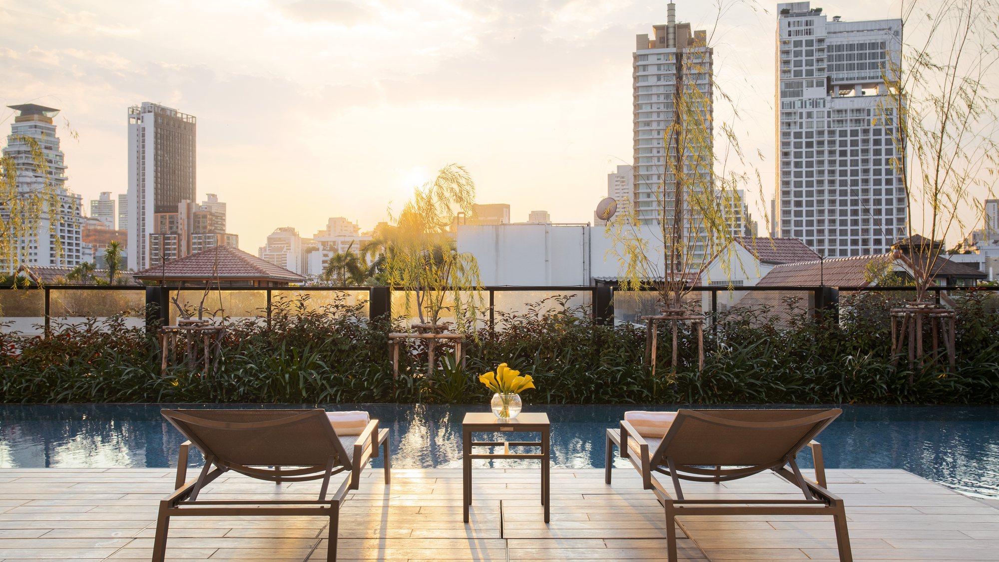 Sun loungers beside the Walton Suites rooftop pool overlooking Bangkok at sunset